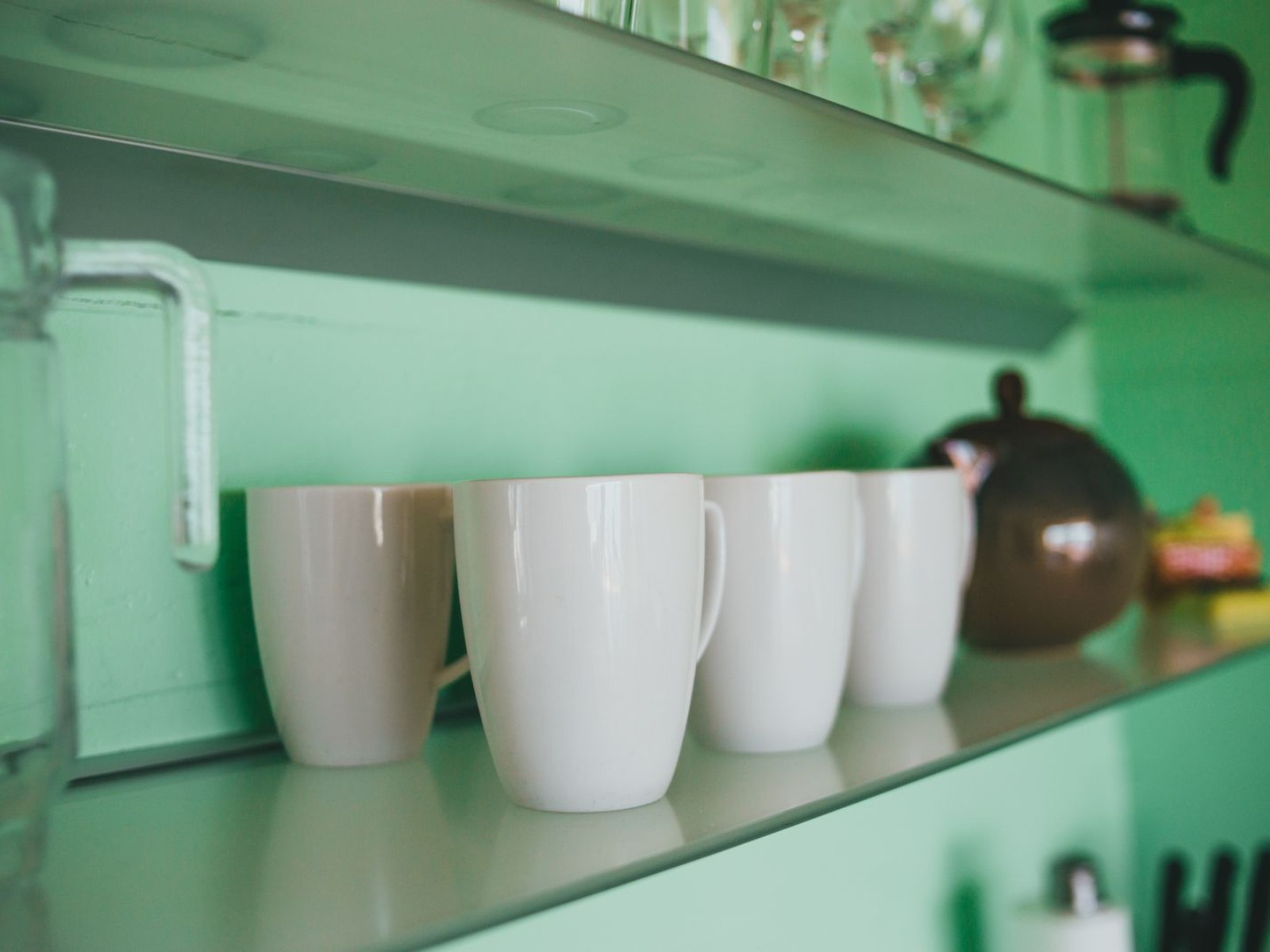 A shelf of mugs anchoring a tidy home coffee bar setup