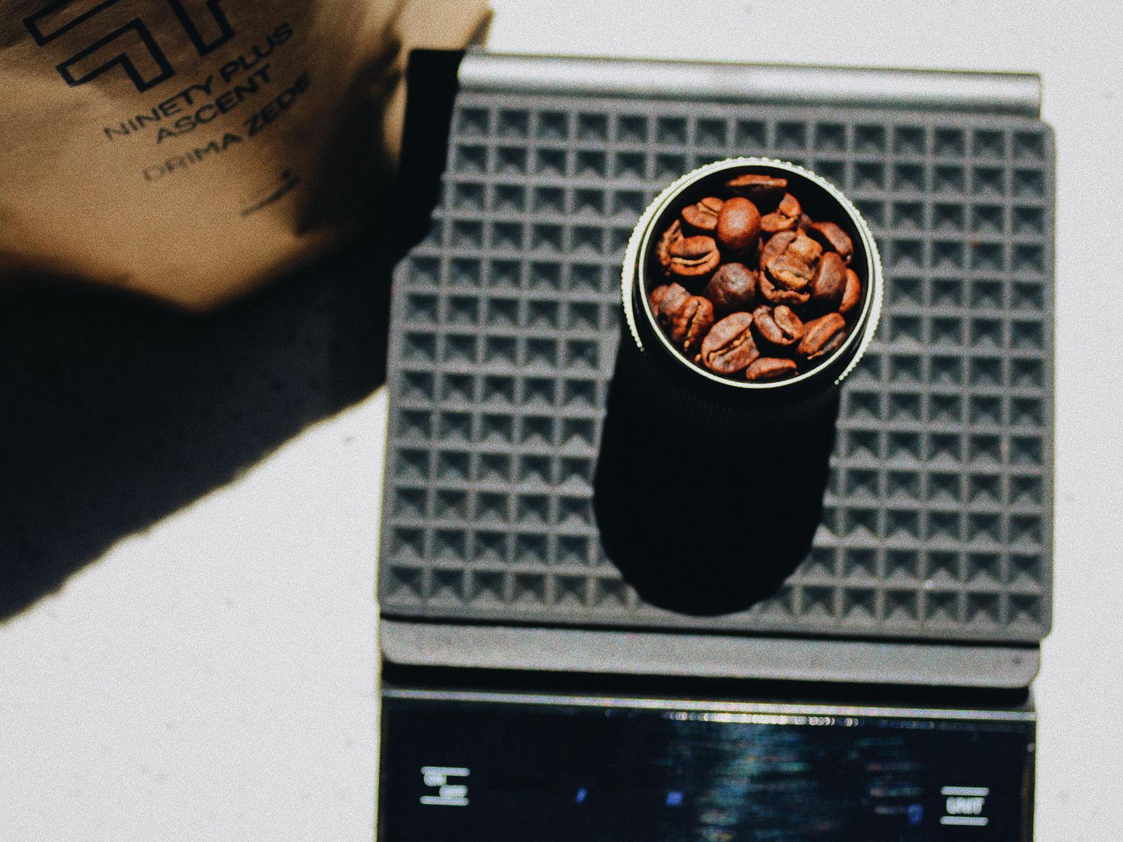 Coffee beans in a measuring cup on a digital kitchen scale