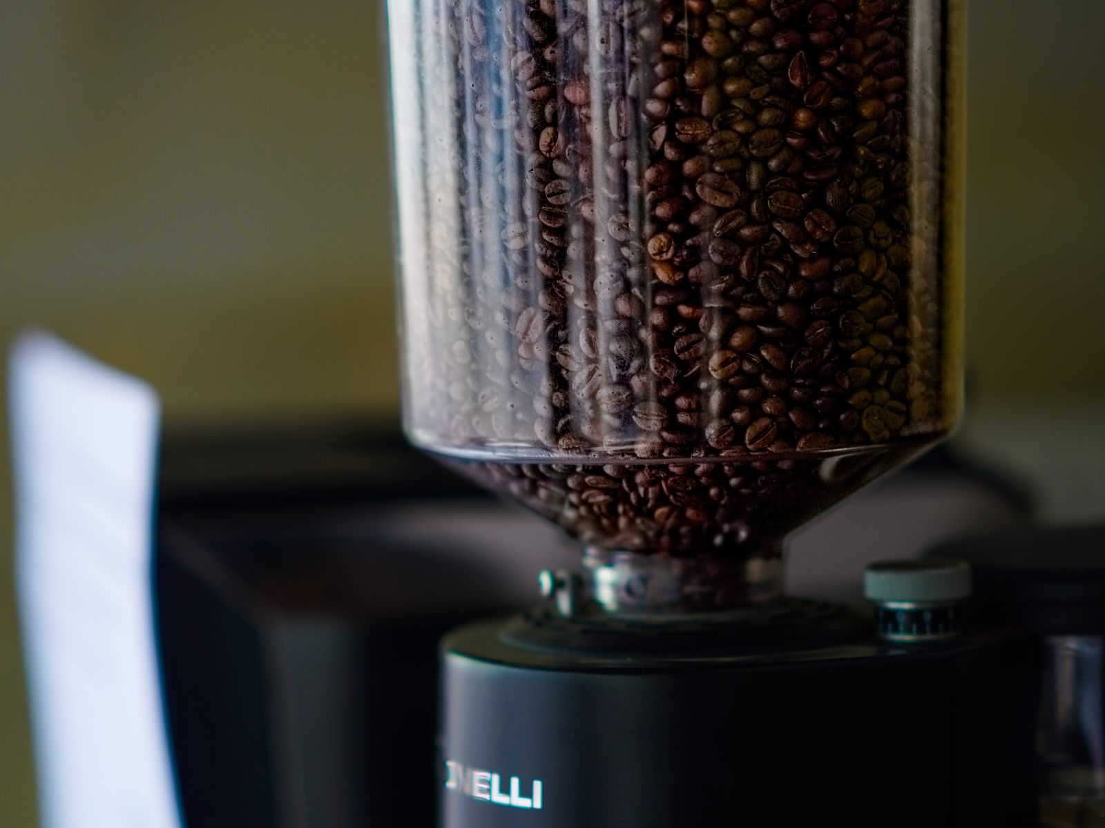 Roasted coffee beans inside a transparent grinder hopper