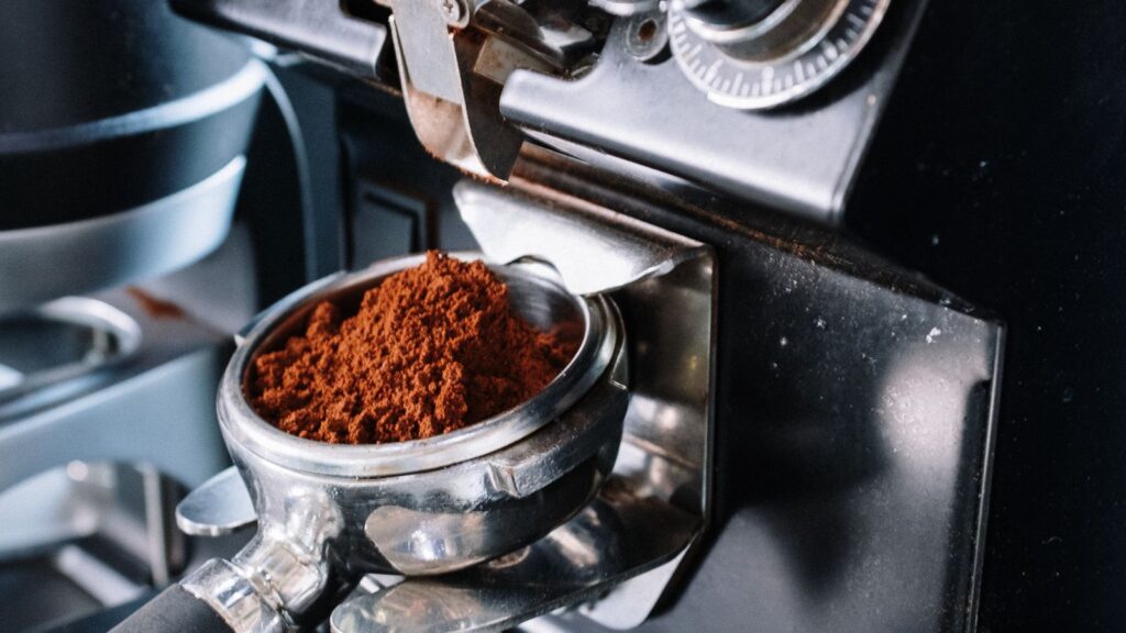 Coffee grinder with a pile of freshly ground coffee