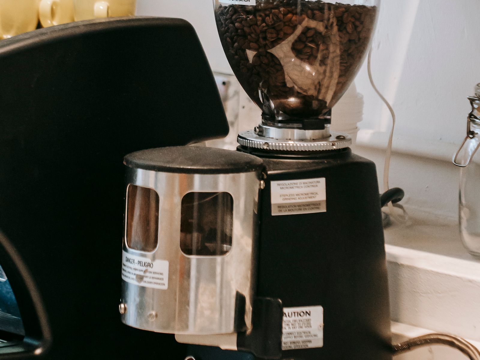 Burr coffee grinder on a home kitchen counter next to fresh beans
