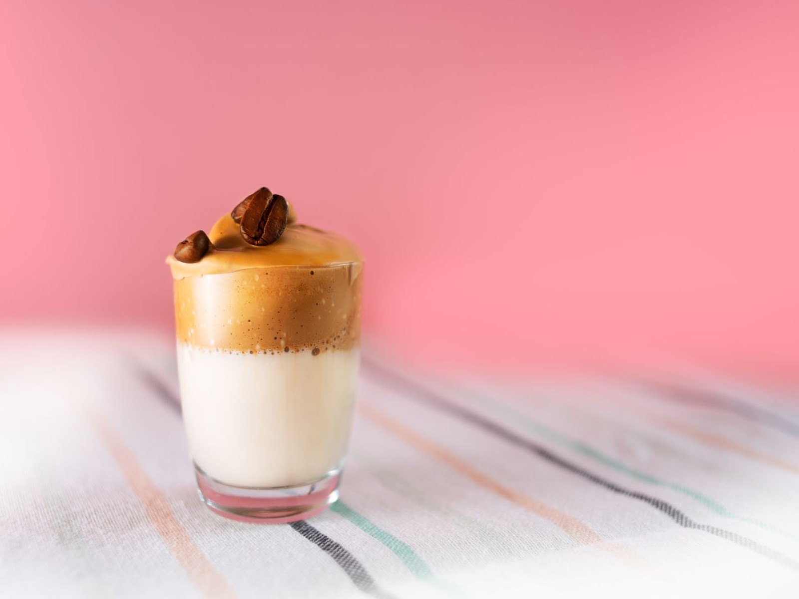 Dalgona coffee foam topped with whole coffee beans in a glass