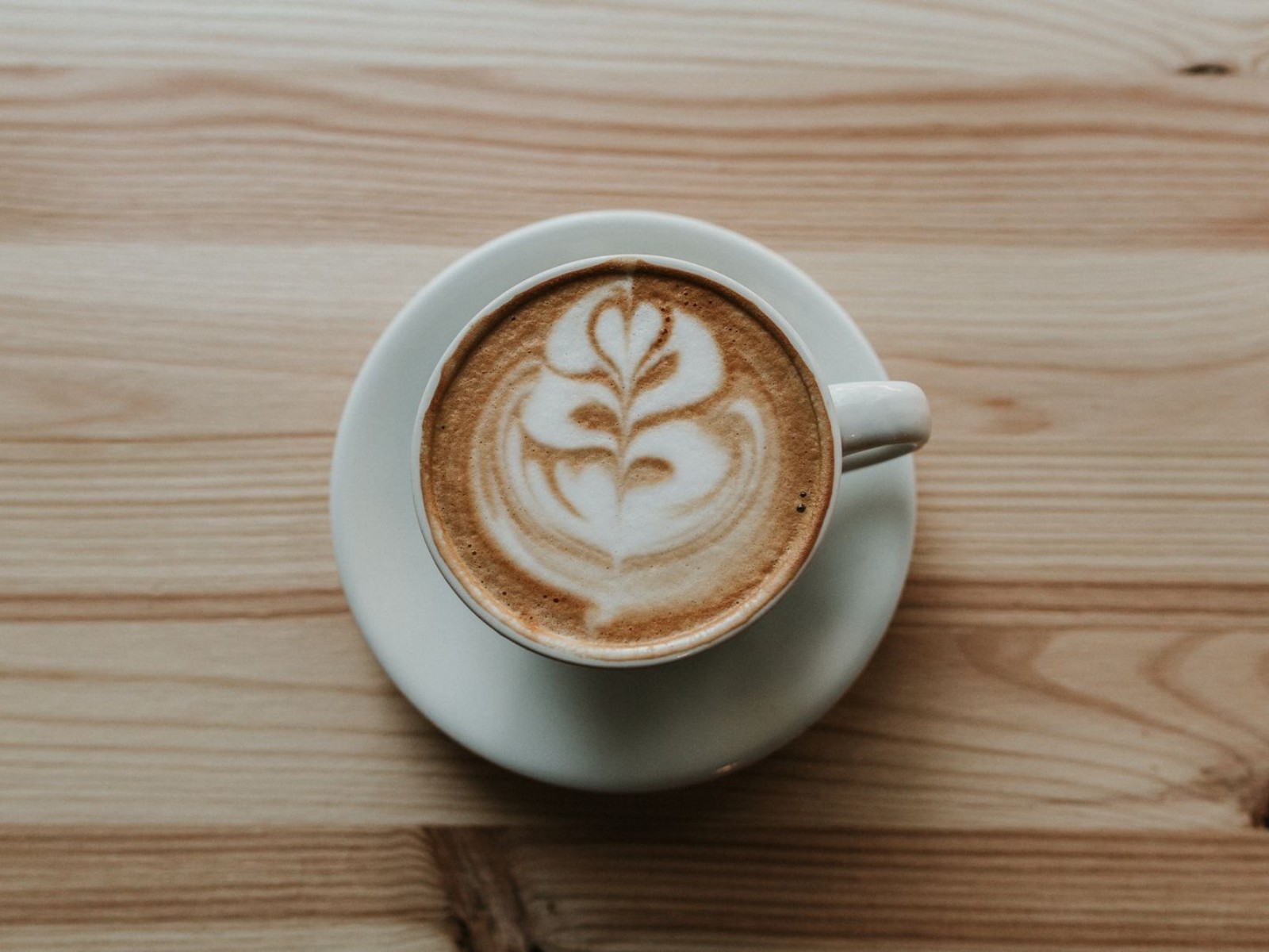 Finished flat white with simple latte art on a wooden table