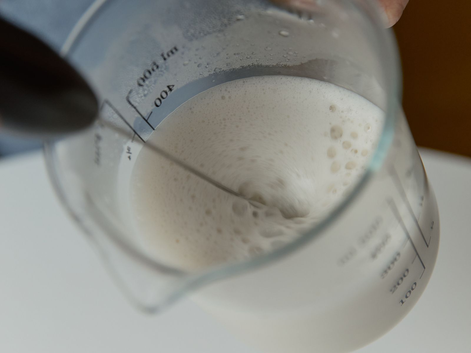 Frothing milk in a measuring cup to create foam at home