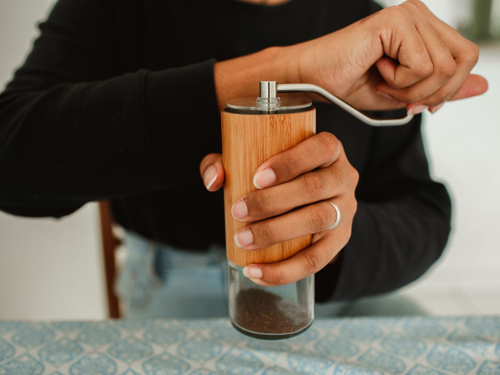 Person grinding coffee beans with a manual grinder