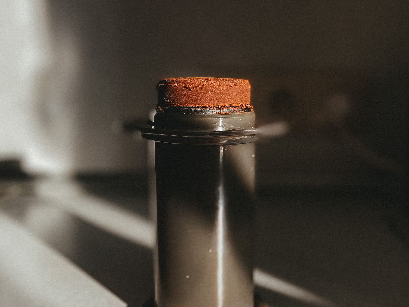 Ground coffee beans in an AeroPress chamber on a kitchen table
