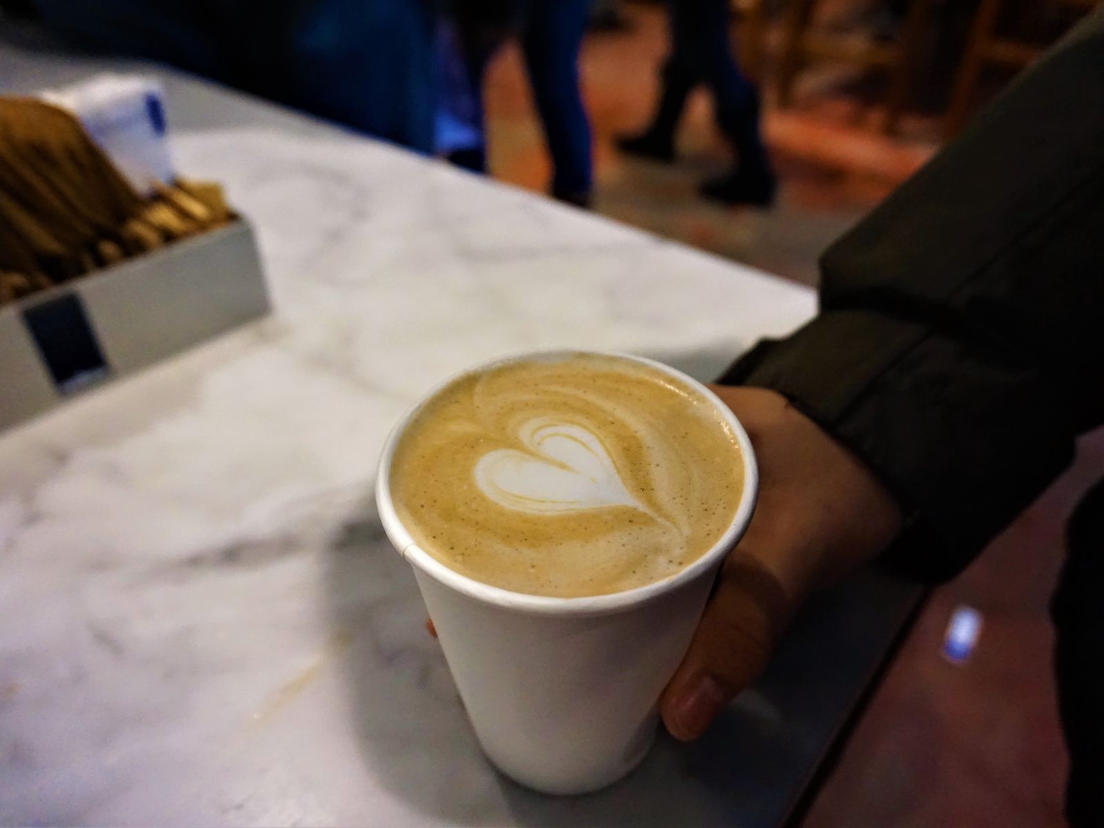Hand holding a cup of coffee with heart latte art