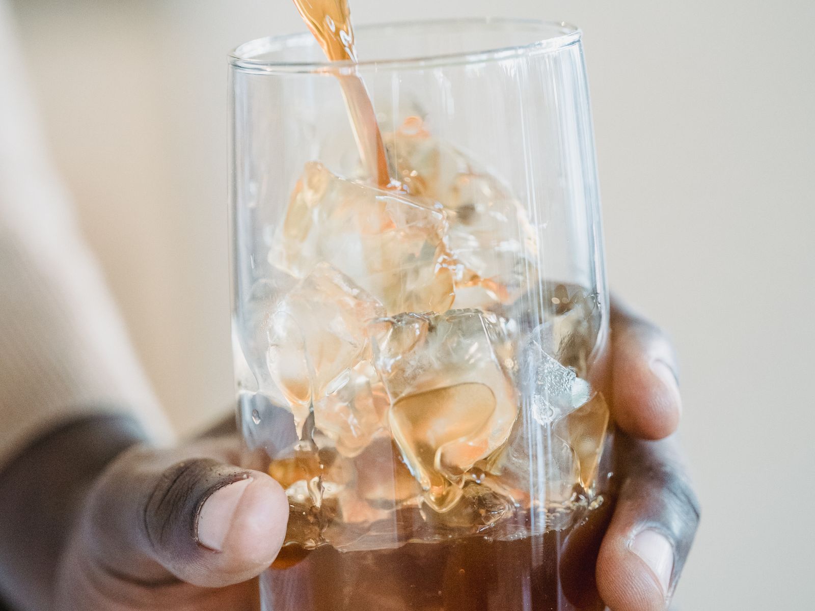 Iced cold brew coffee being poured over ice into a glass