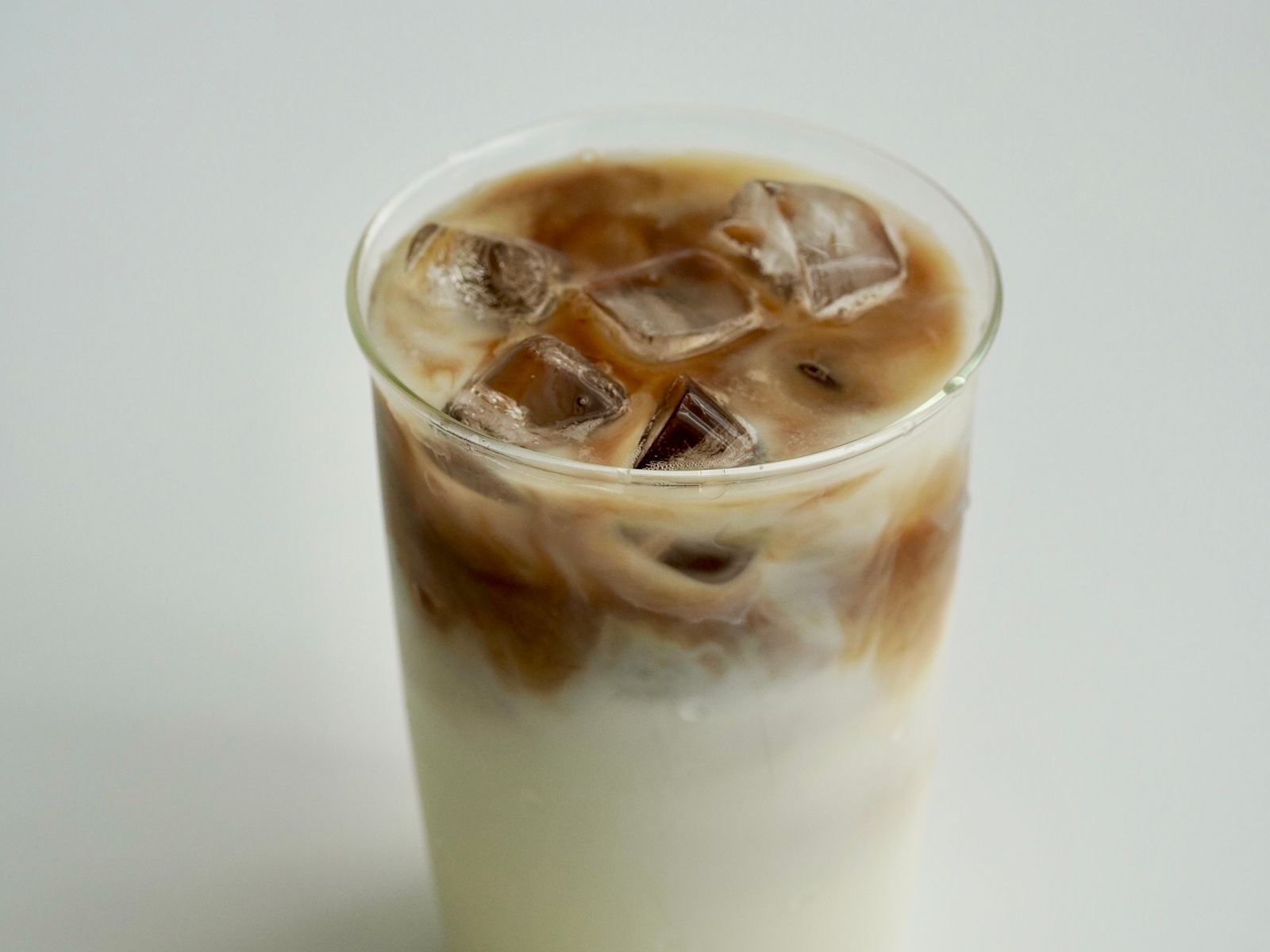 Iced latte at home showing coffee and milk poured over ice in a clear glass