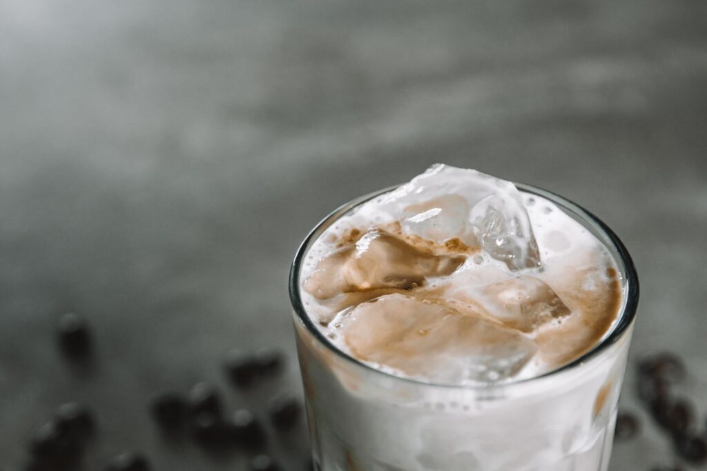 Iced latte at home with frothy milk and ice cubes in a glass