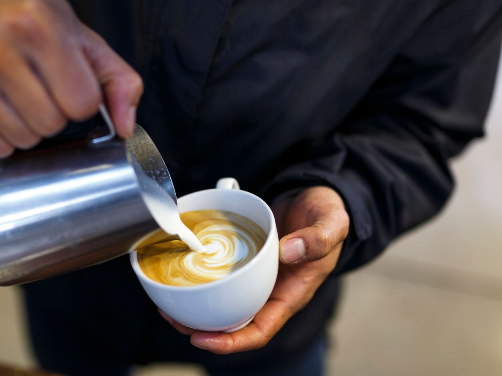 Barista pouring milk correctly, avoiding common latte art mistakes