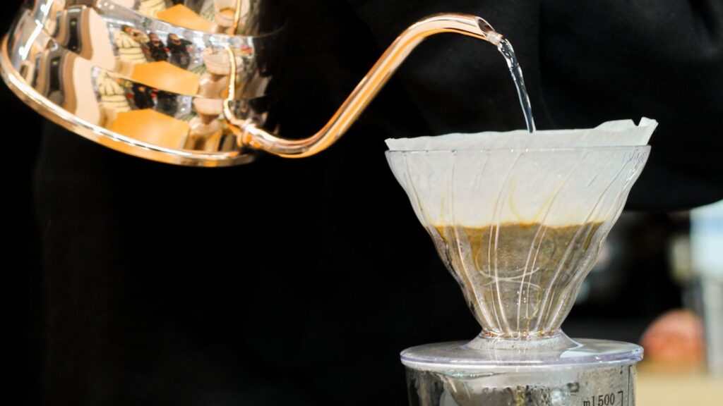Hands pouring water over coffee grounds in a pour-over dripper
