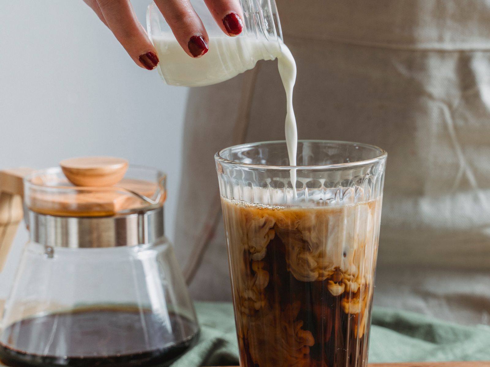 Pouring milk into a glass of cold brew coffee