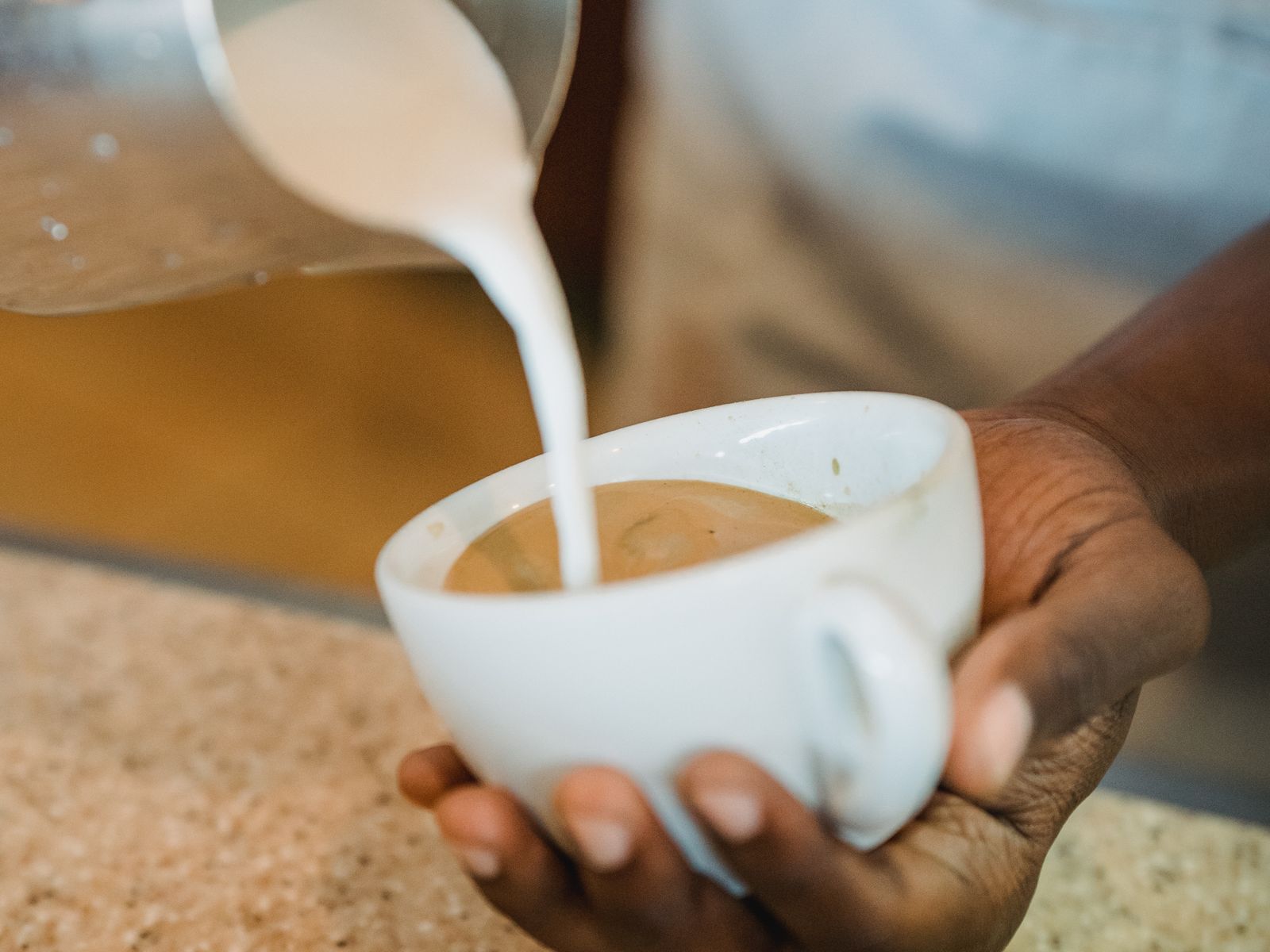 Barista pouring steamed milk to make latte art