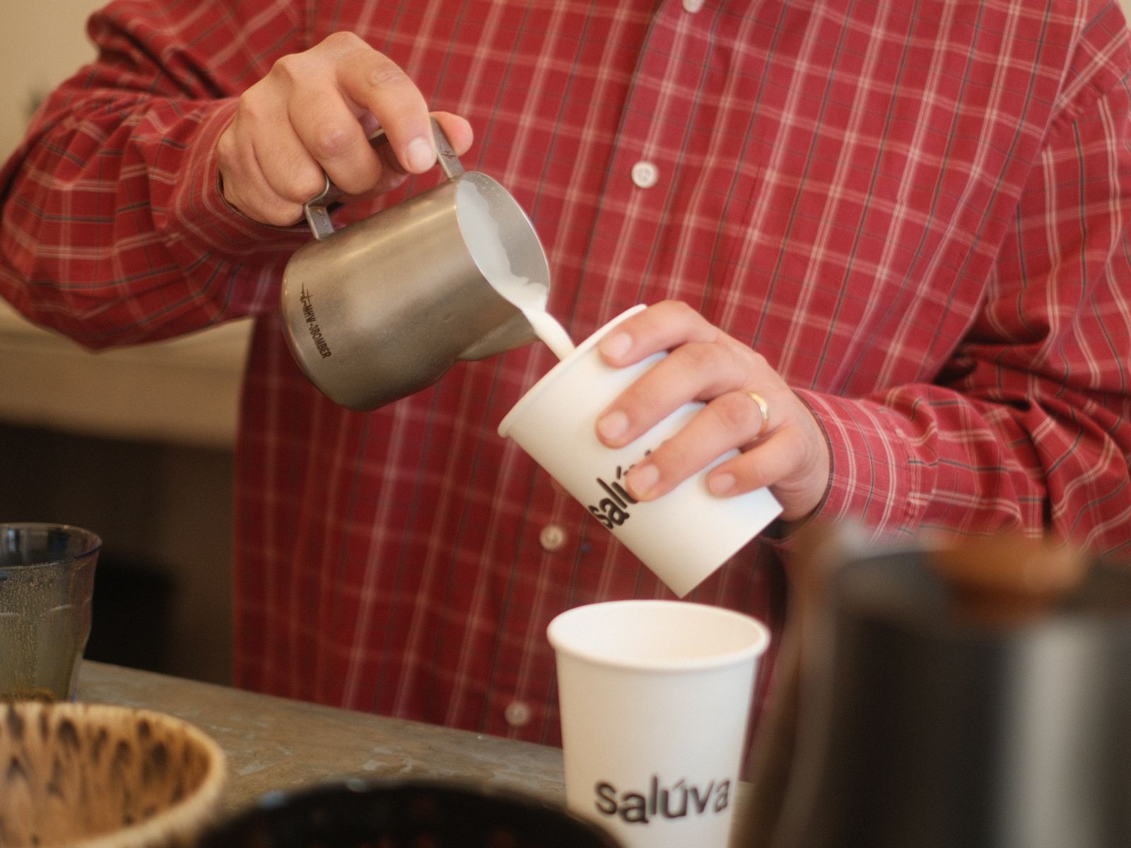 Barista pouring steamed milk into a coffee cup to finish a latte