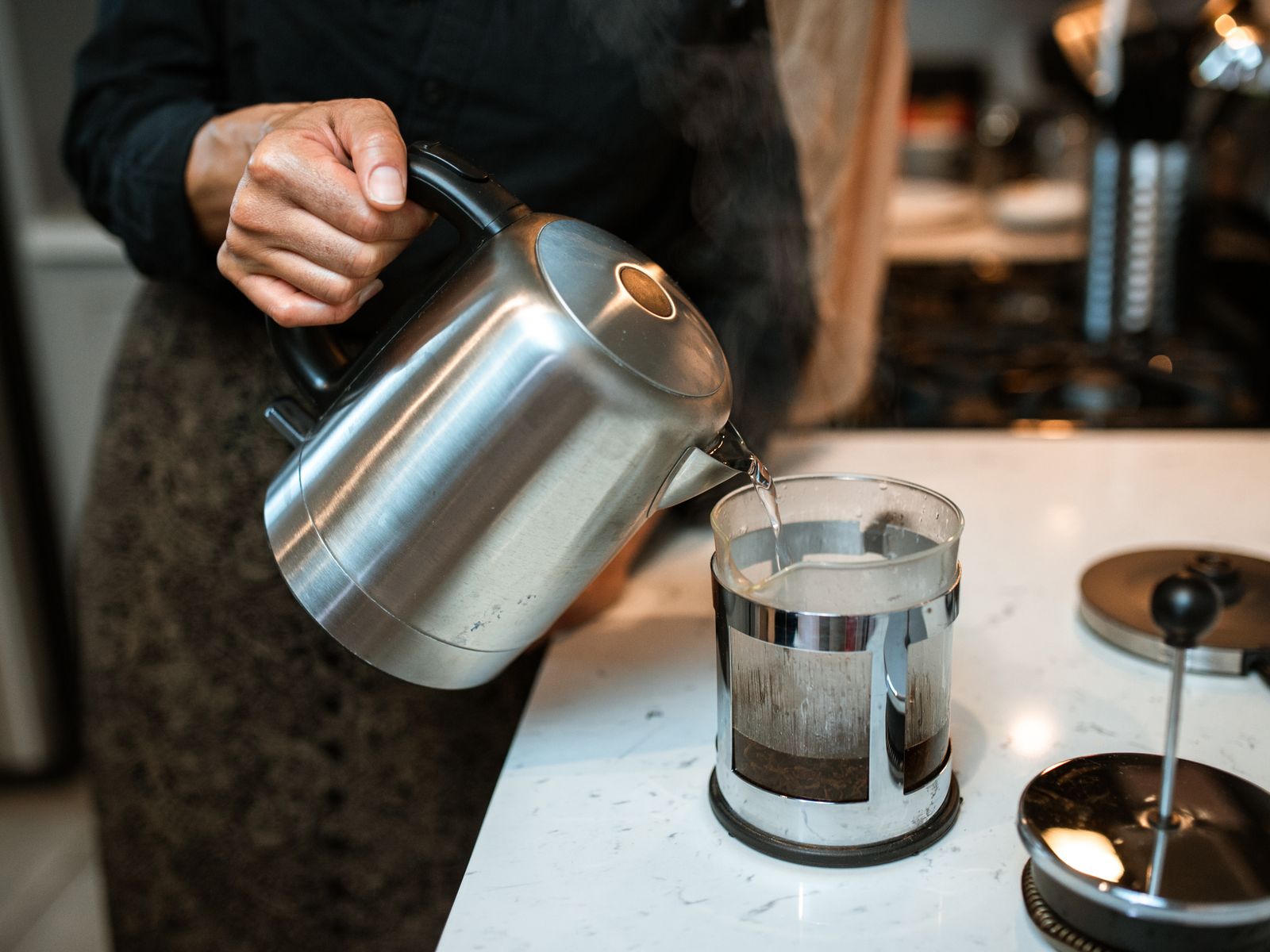 Pouring hot water into a French press full of coffee grounds