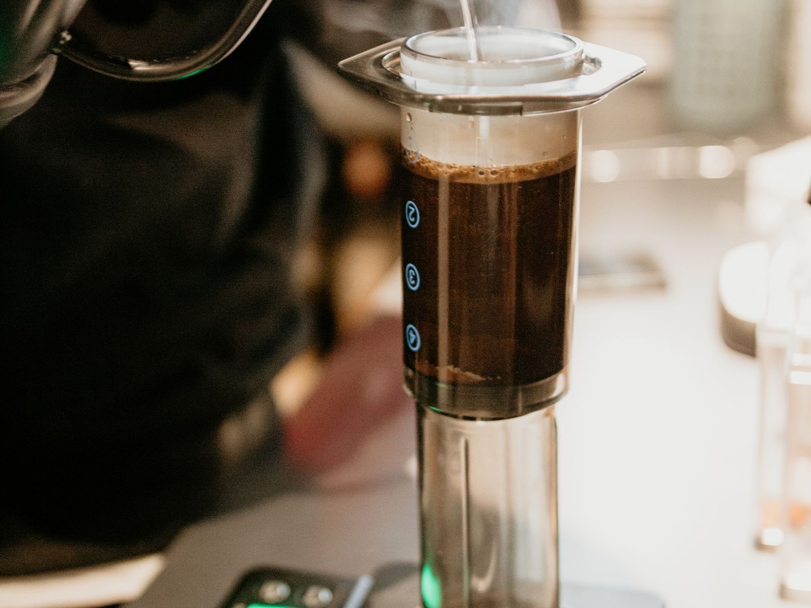 Pouring hot water from a gooseneck kettle into an AeroPress on a scale