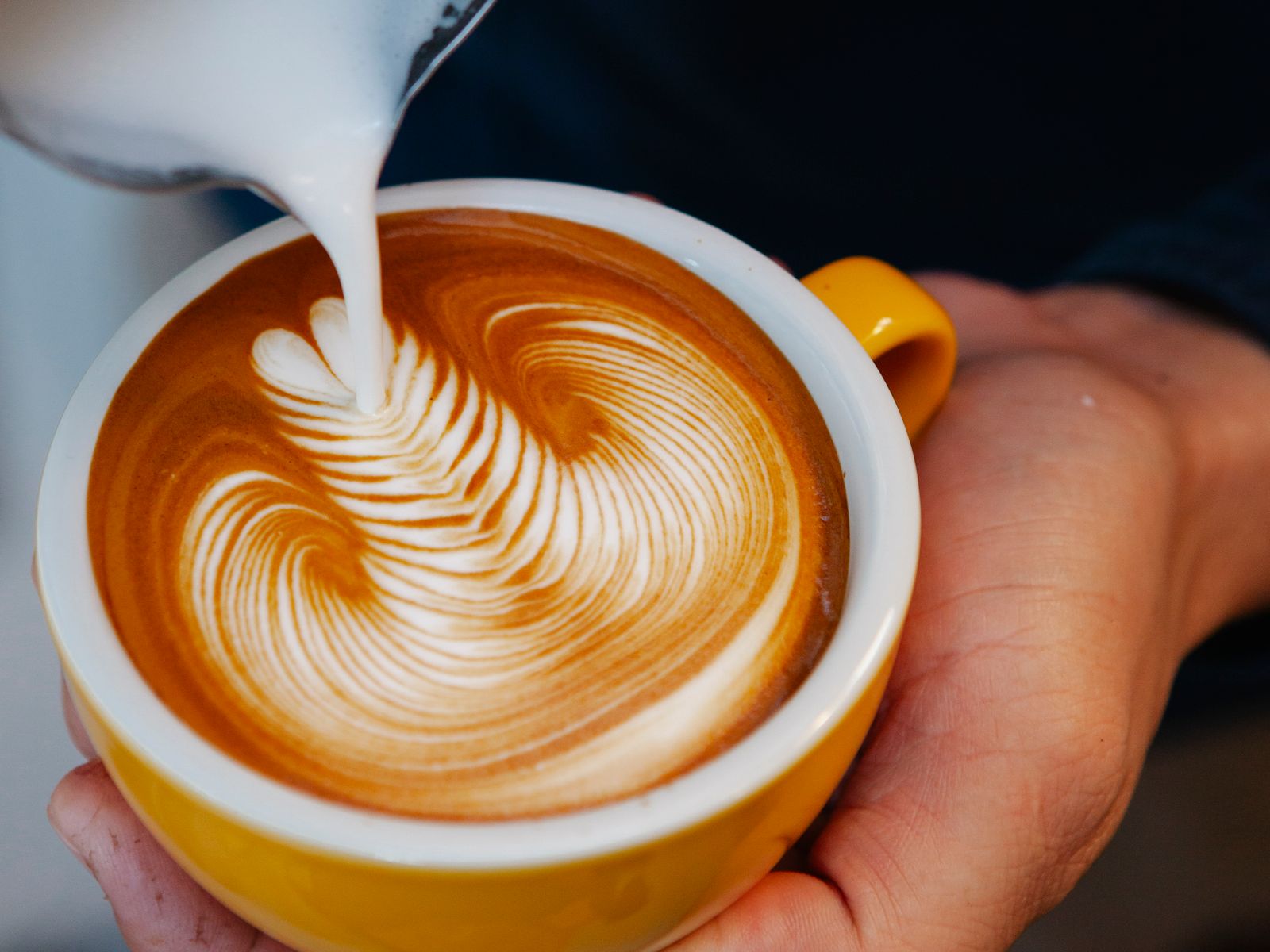 A barista practicing pouring milk for latte art