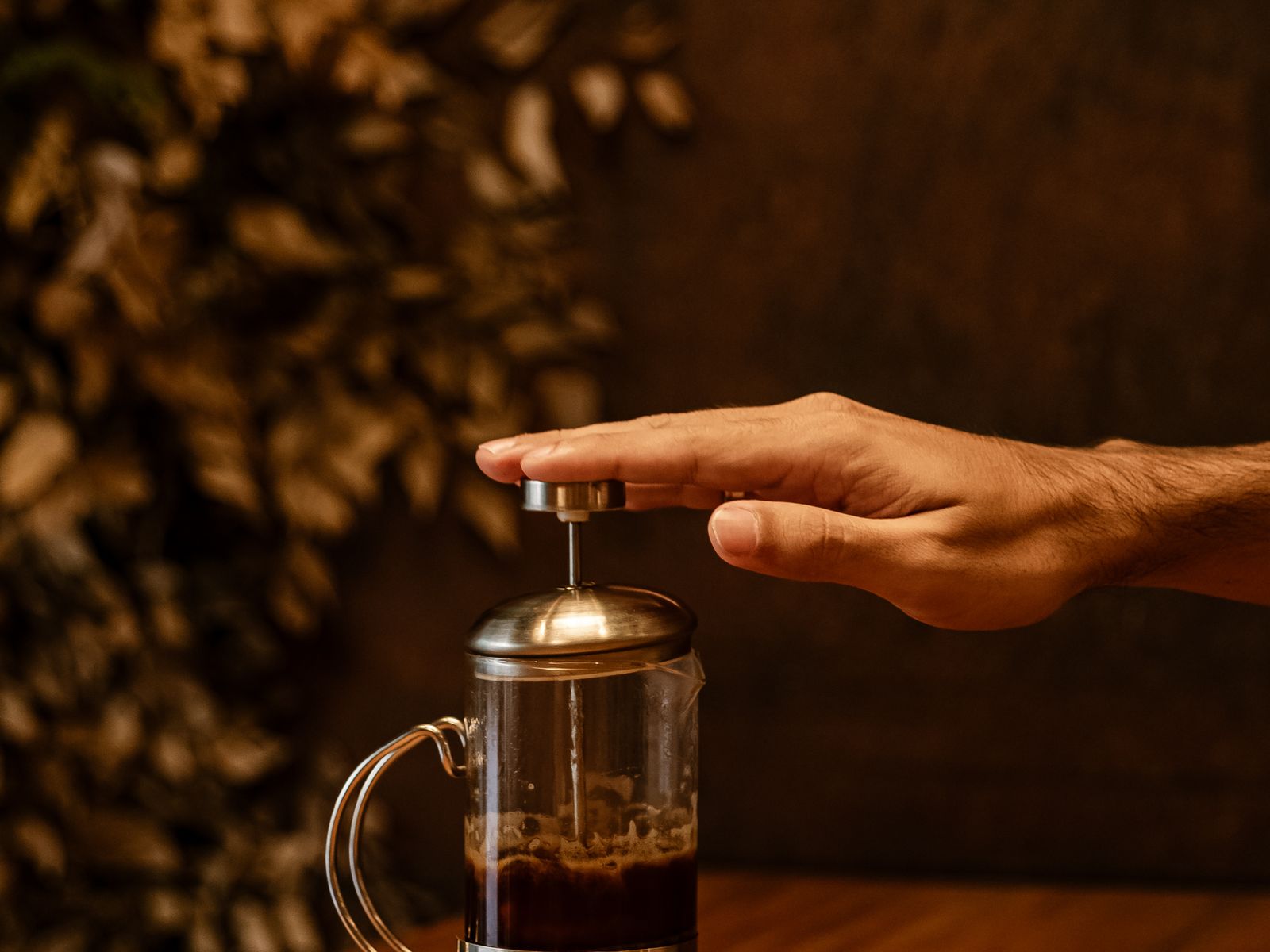 Hand slowly pressing down the plunger on a French press