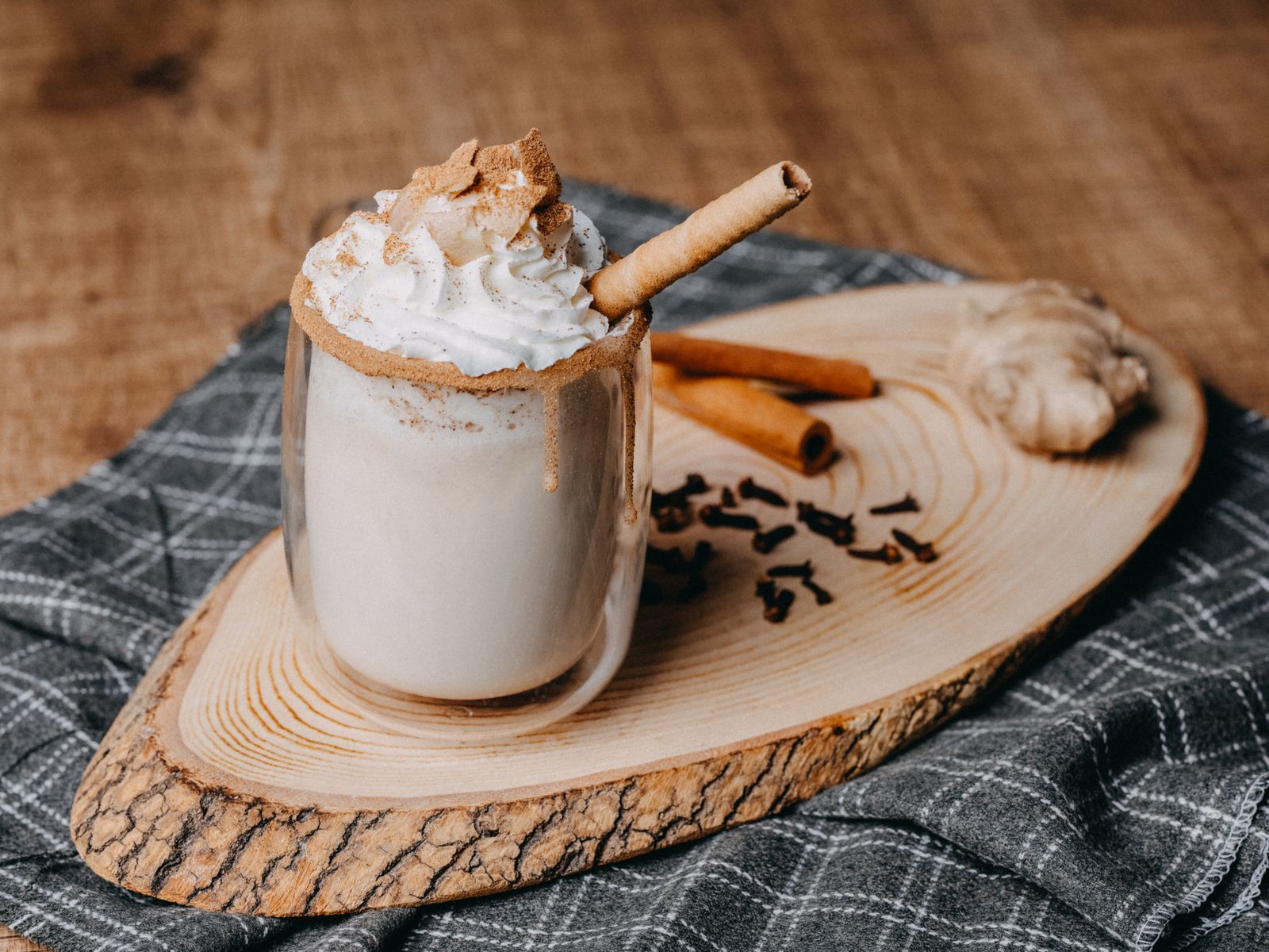 A spiced latte topped with whipped cream and cinnamon on a wooden table