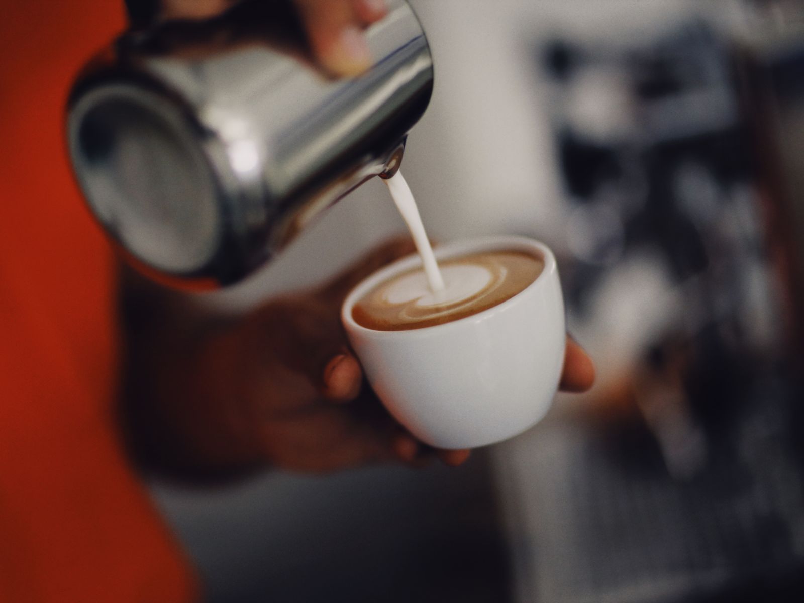 Barista pouring silky steamed milk microfoam to create latte art