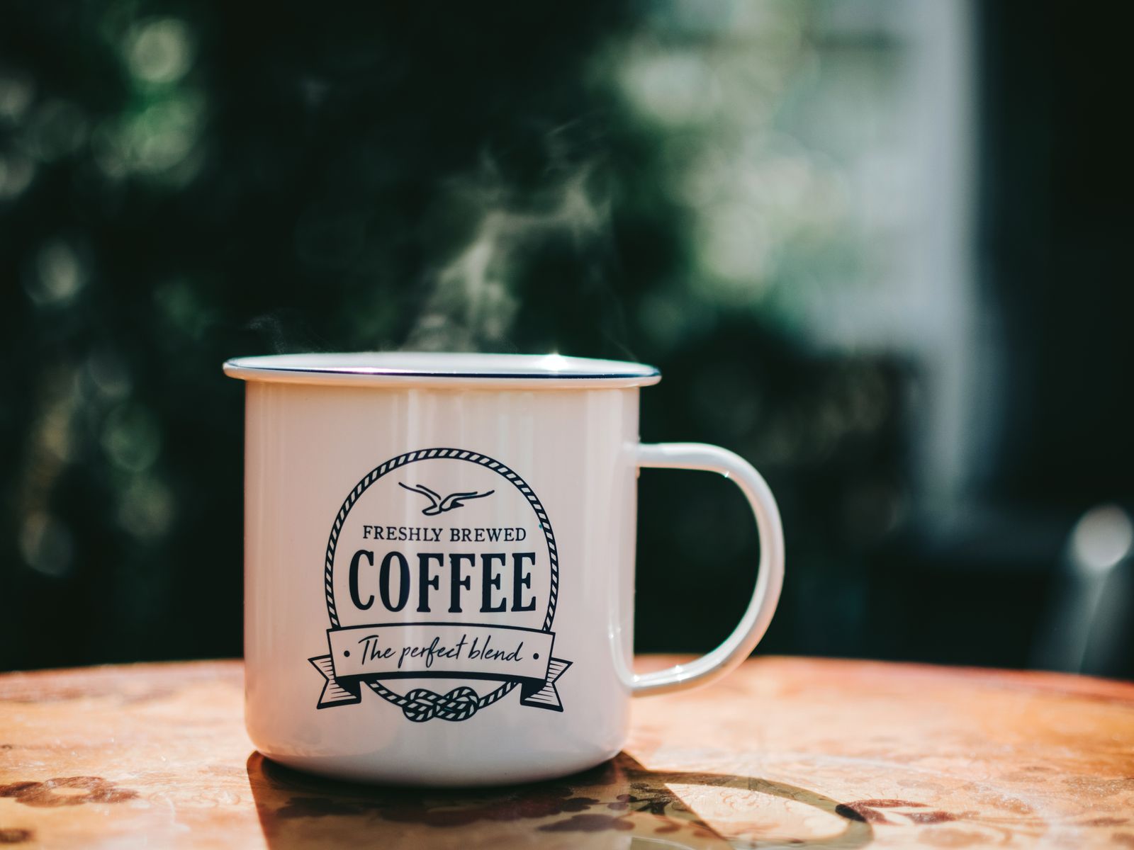 Steaming mug of coffee on a wooden table in the morning