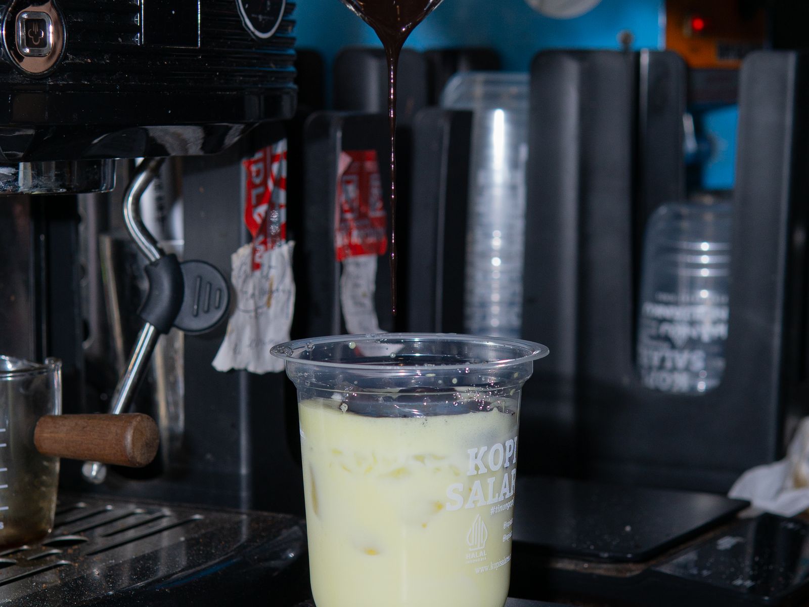 Flavored syrup being poured into a glass of iced coffee