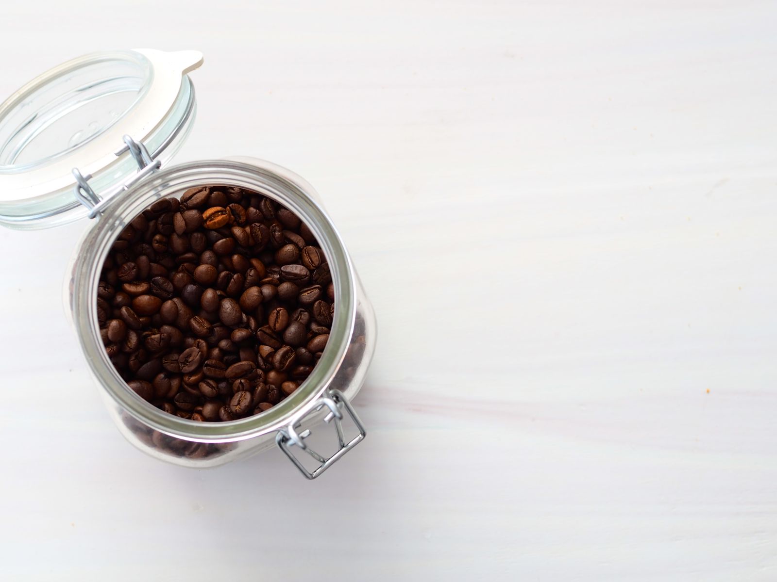 Top view of a glass jar filled with whole roasted coffee beans