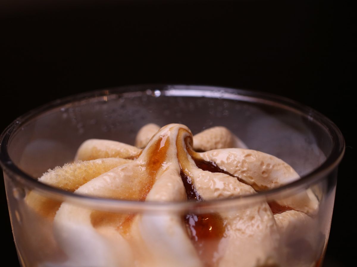 A close-up of an ice cream dessert topped with coffee syrup