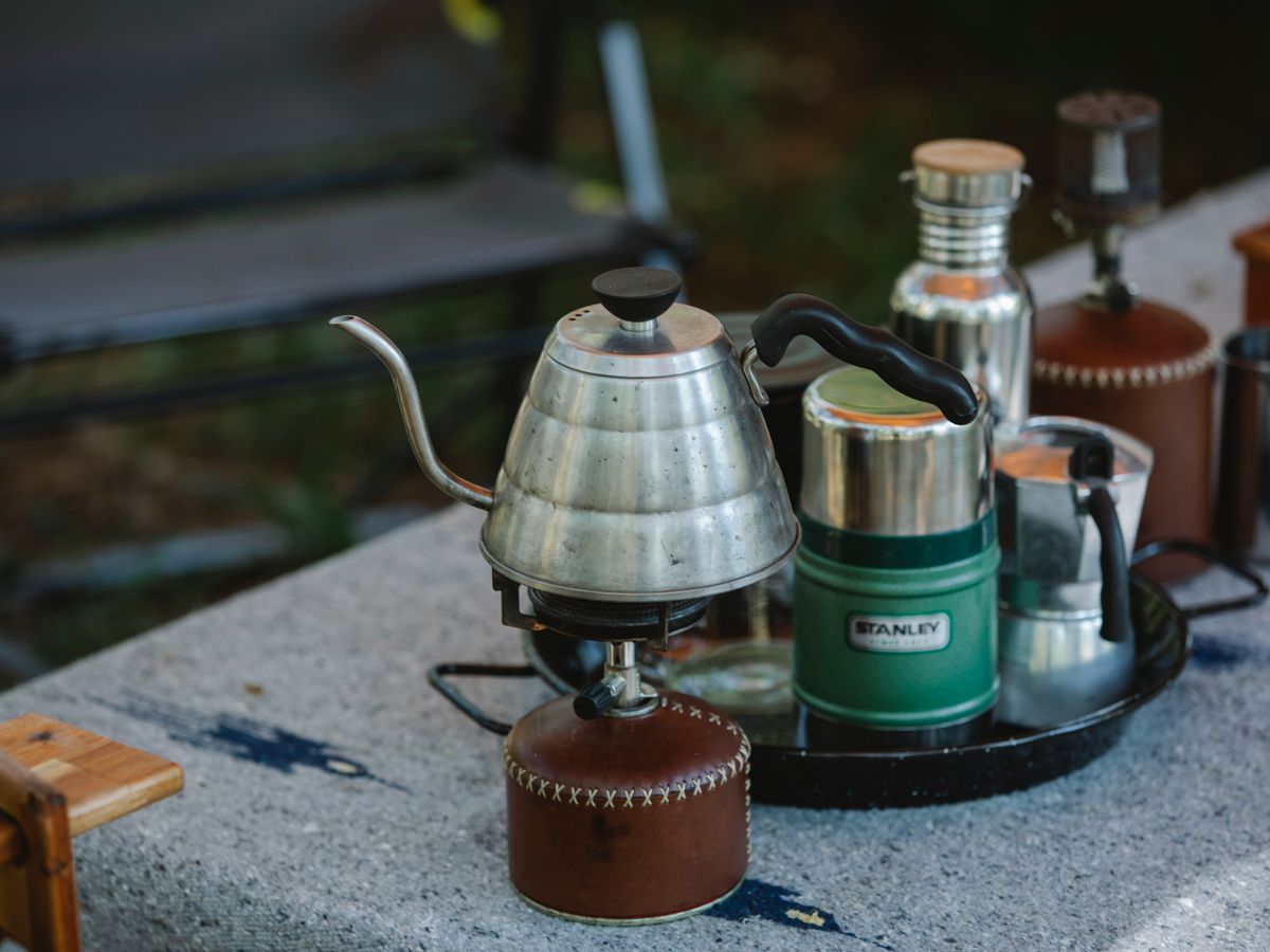 A metal coffee kettle on a small portable camping stove