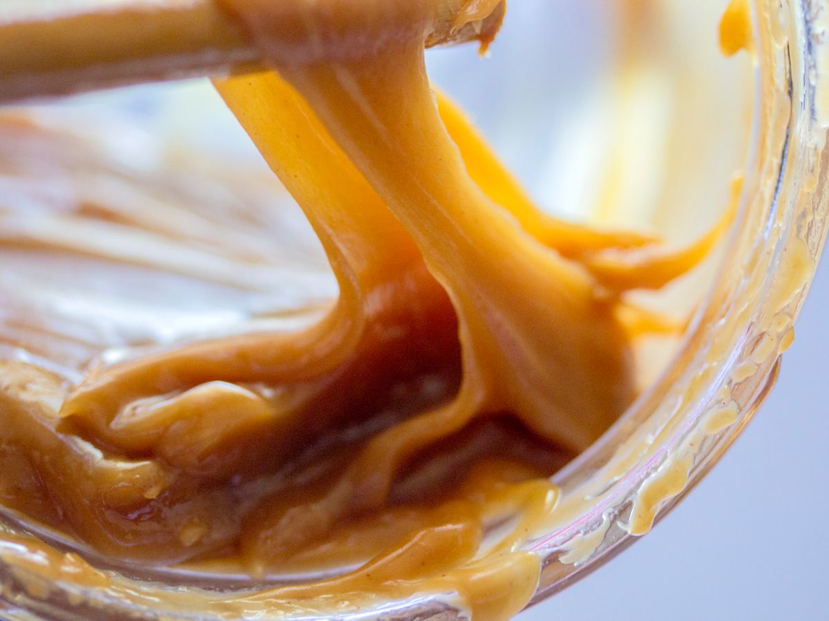 Glossy amber caramel on a whisk while making caramel syrup