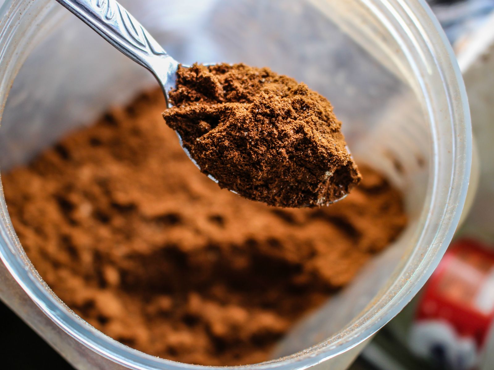 Scooping unsweetened cocoa powder from a jar to make a mocha