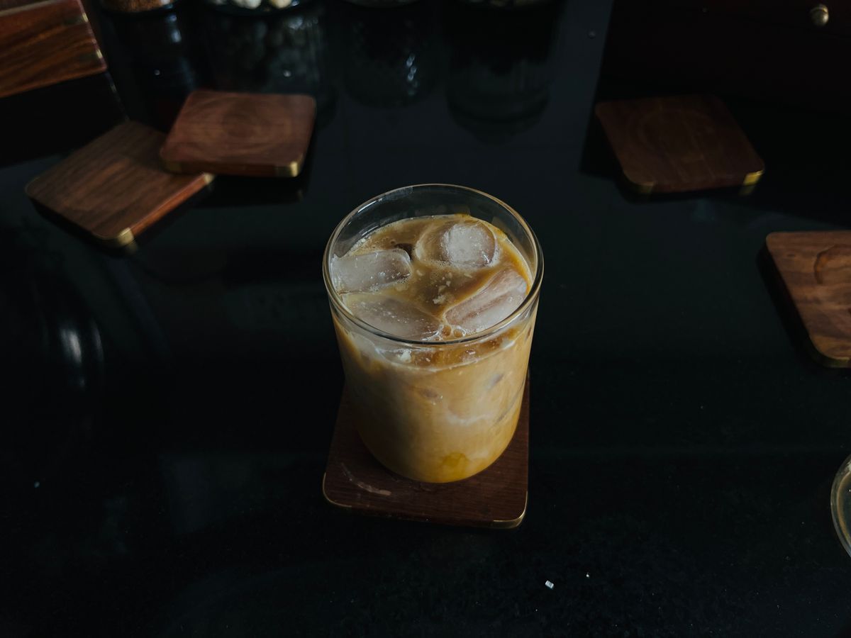 A tall glass of smooth cold brew coffee on a dark wooden table
