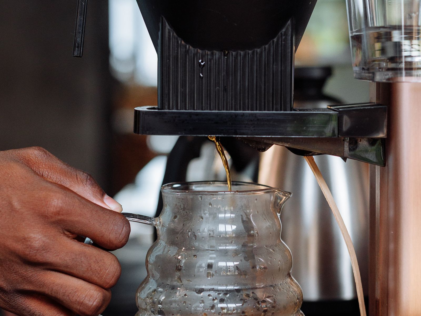 A drip machine brewing coffee into a carafe, where warming-plate settings matter