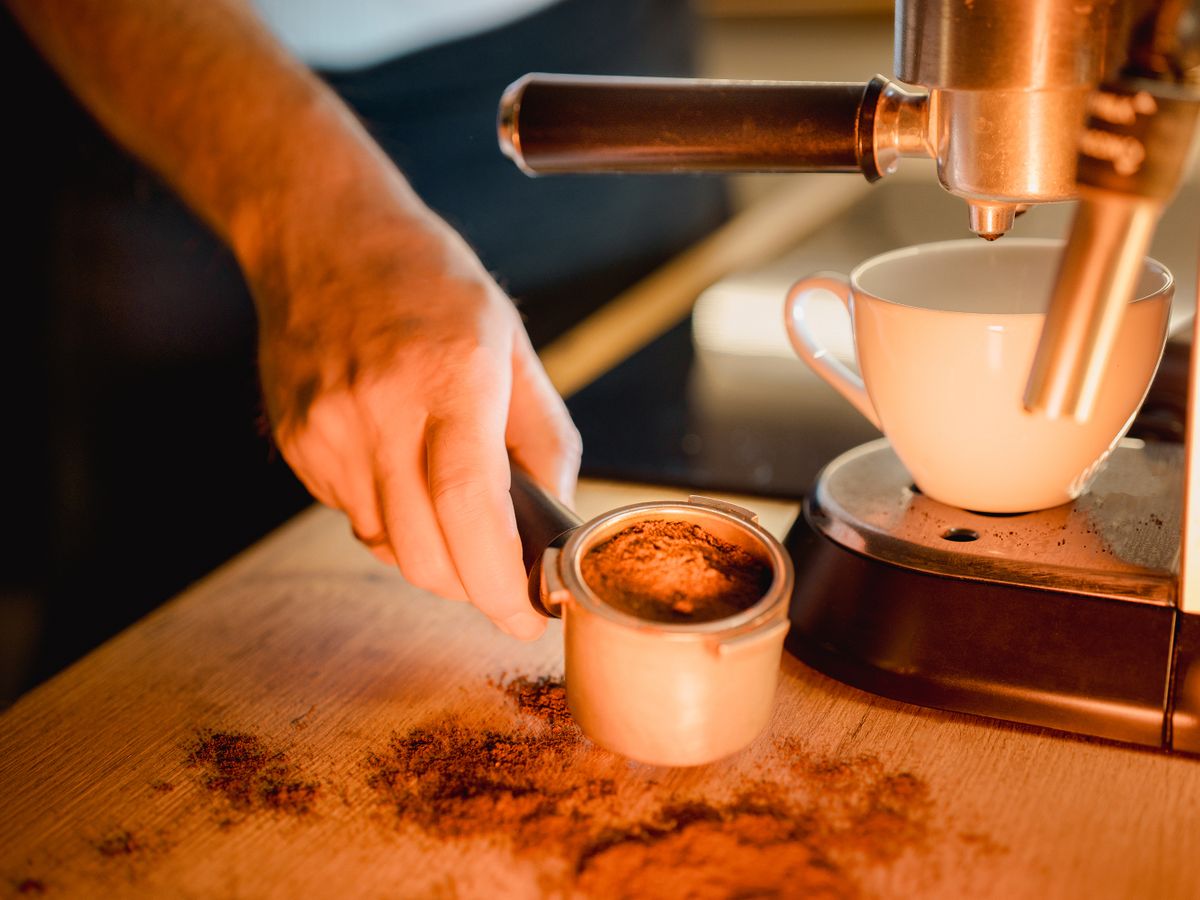 A hand preparing espresso with a portafilter on a home machine