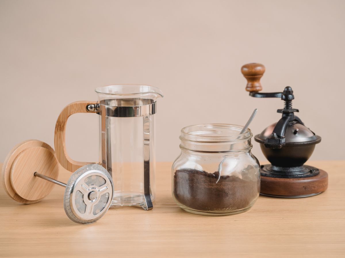 A French press with its mesh plunger screen that creates milk foam