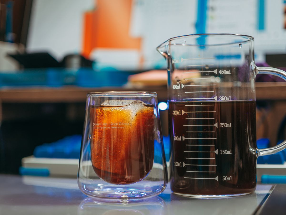 A close-up of flash-chilled iced coffee beside a measuring beaker