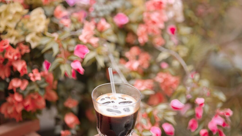 Iced coffee recipes for summer: a cold coffee held against summer flowers