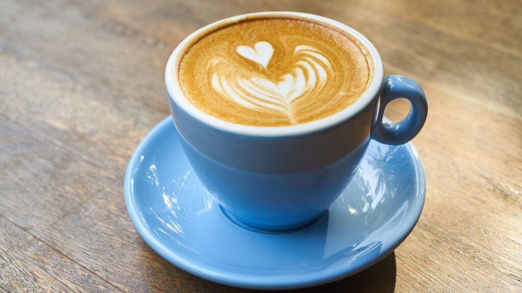 Latte vs cappuccino: a milk coffee drink with heart latte art in a blue cup