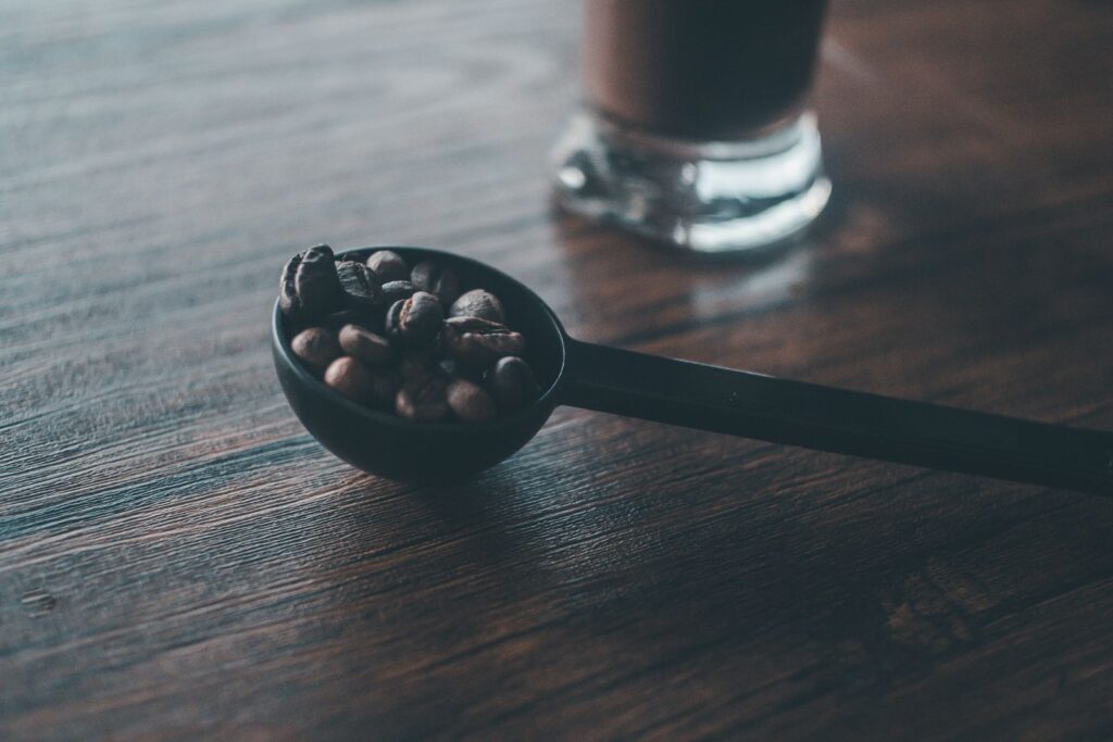 Coffee beans on a black scoop showing how to measure coffee without a scale