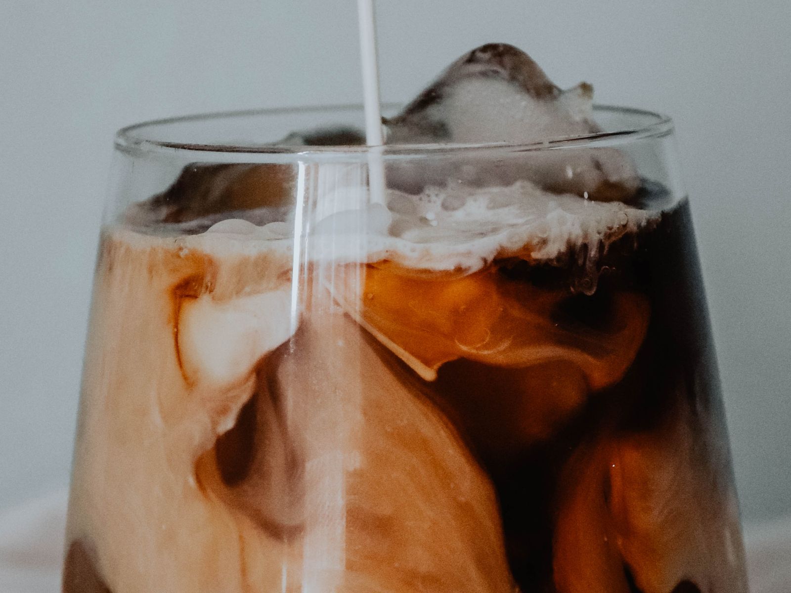 Cold milk poured into iced coffee, swirling through the glass