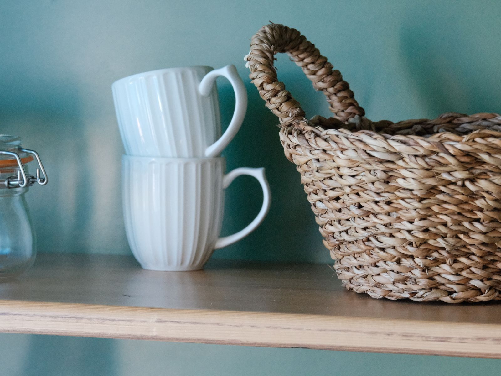 Mugs and a storage jar on a floating shelf to save counter space