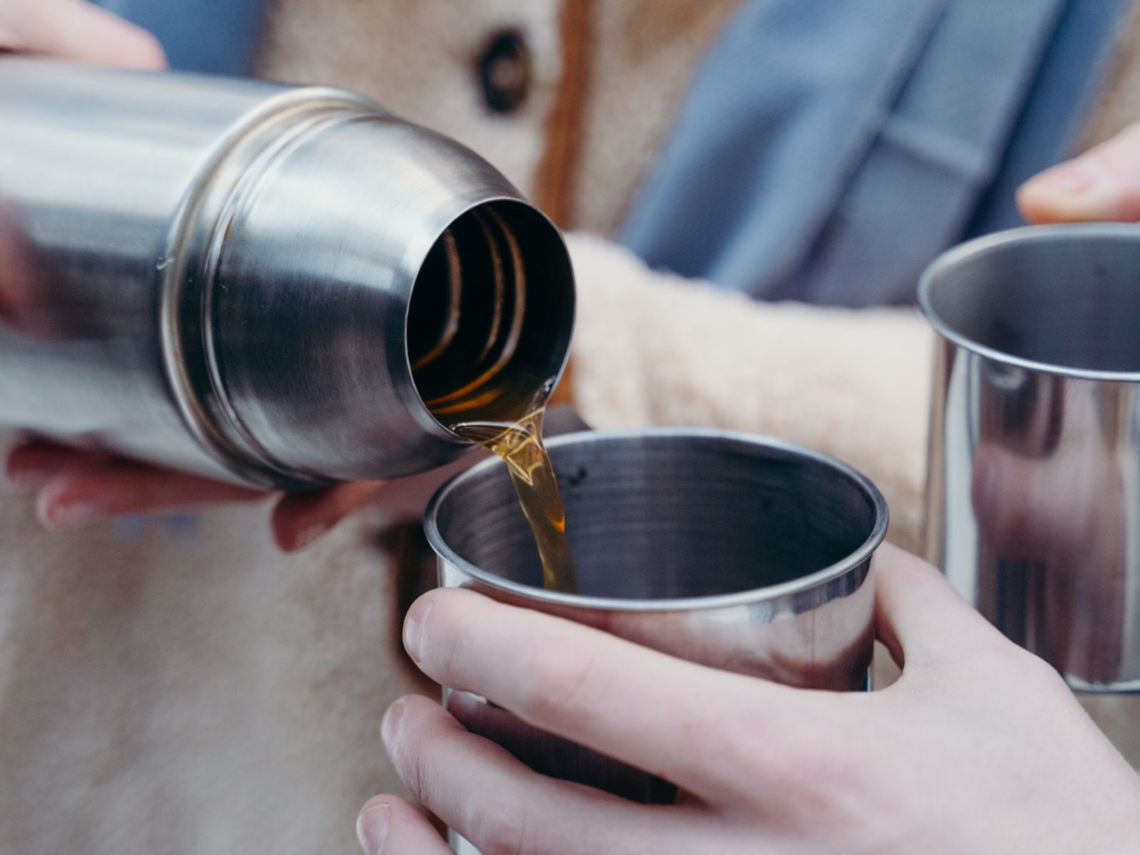 Pouring coffee from an insulated thermos flask to keep coffee hot without cooking it