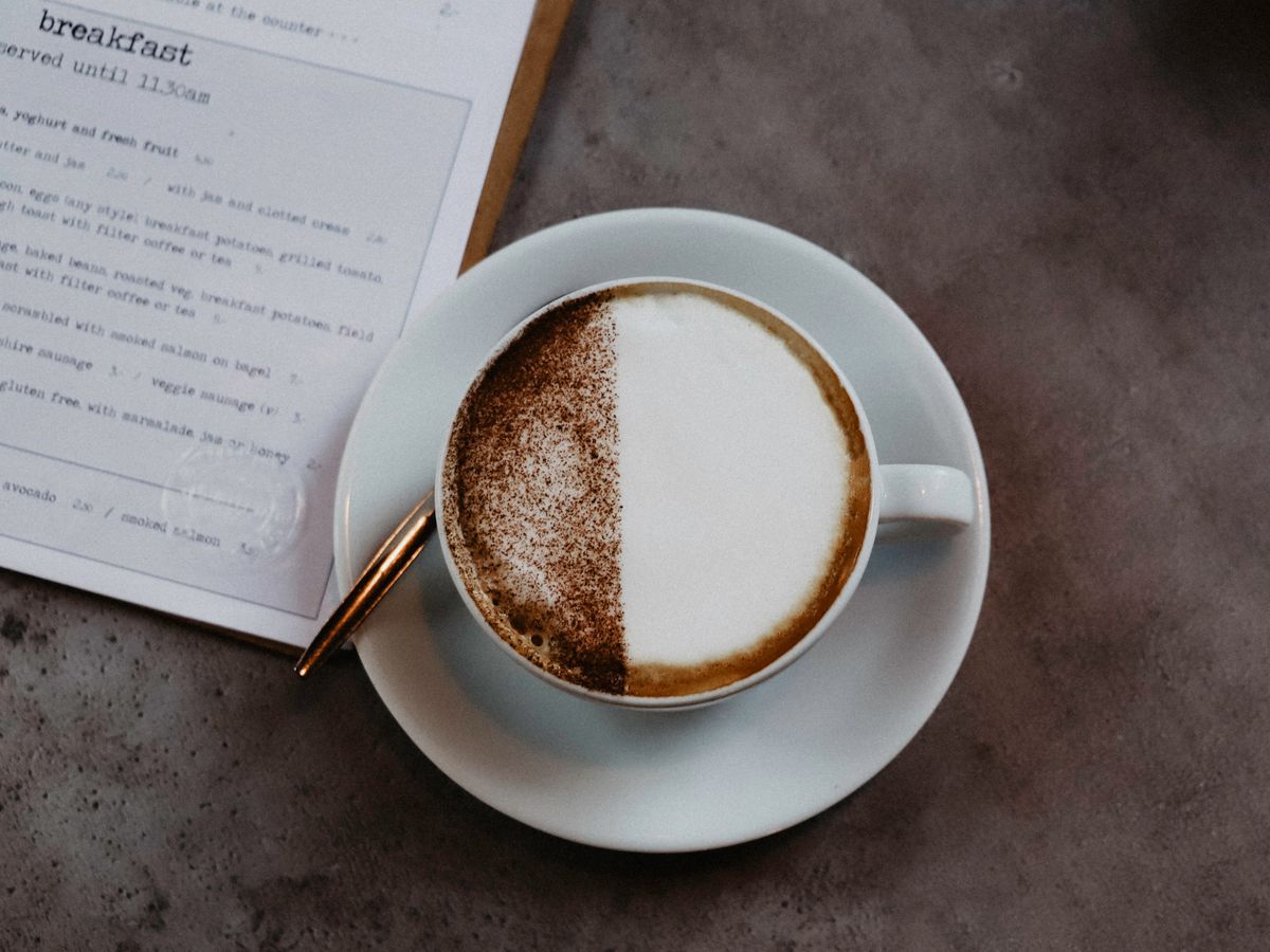 Frothed milk being poured over coffee to make foam