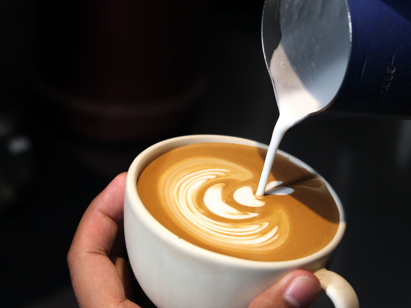 A latte being made in the latte vs cappuccino comparison, with milk poured for art