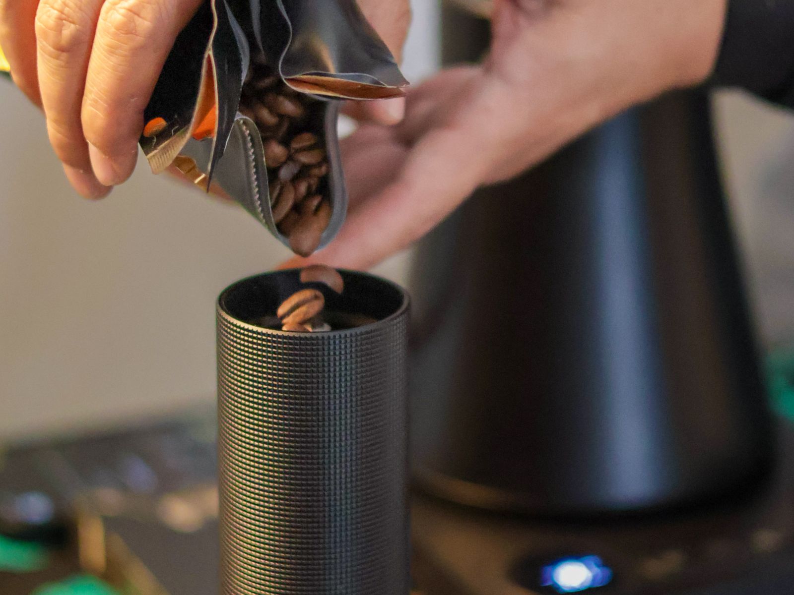 Pouring whole coffee beans into a grinder to keep the beans fresh