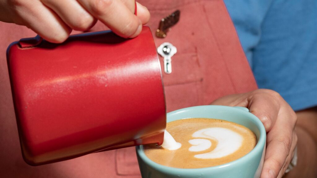 Practice latte art by pouring milk from a pitcher into a cup
