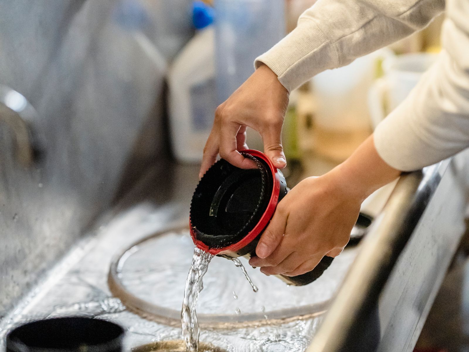 Rinsing a reusable coffee filter under running water to keep it clean