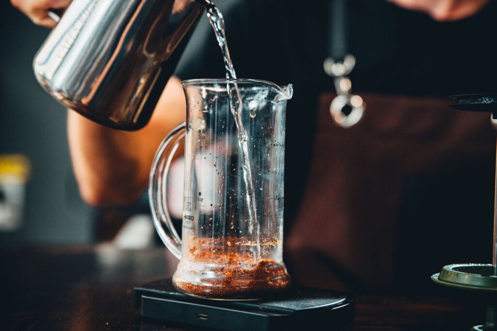 Pouring water for coffee into a glass pitcher with coffee grounds